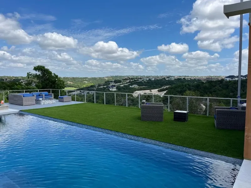 Artificial turf lawn beside an infinity pool overlooking the Austin hills